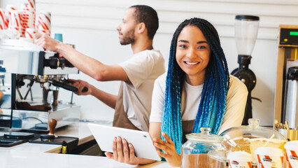 Happy African American woman using digital tablet in cafe