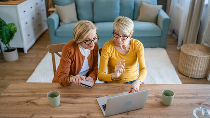Fototapeta premium Senior women two females hold credit card online shopping at home