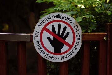 A round sign on a wooden fence informing about dangerous animals