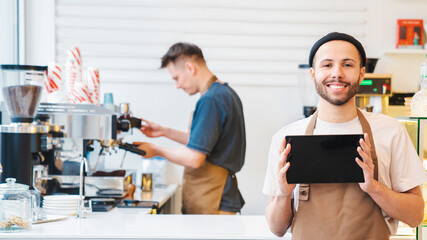 Fototapeta premium Smiling male barista showing digital tablet screen, copy space