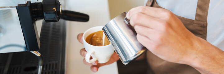 Close up of male hands pouring milk and preparing fresh cappuccino
