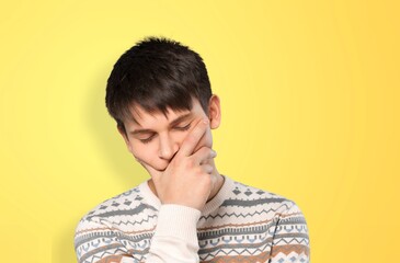 Thoughtful young male student standing on background