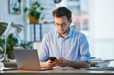 Time to take a break. Shot of a young businessman sending a text using his smartphone.