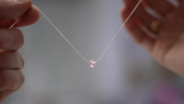 Hands hold a thread with a bead
