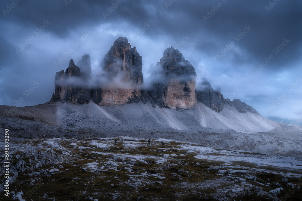 Wall mural rocks in low clouds and moody sky with clouds at twilight in summer. landscape with mountain peaks i