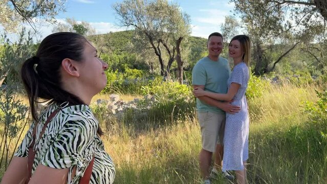 Photographer girl taking pictures of smiling man and woman in olive grove