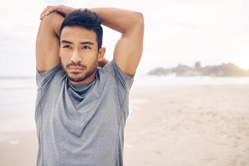 What the mind can conceive, the body can achieve. Shot of a sporty young man stretching his arms while exercising on the beach.