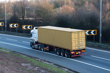 Lorry carrying shipping container travelling on the British motorway.