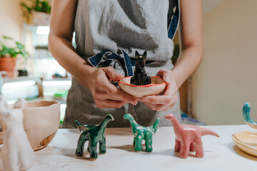 Young woman holding ceramic dinosaur figurines - obrazy, fototapety, plakaty