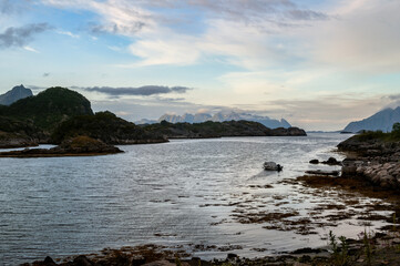 Sunset in the evening during the polar night in Norway. Sea and high rocky mountains with clouds.