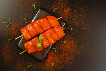 Fresh raw marinated chicken fillet skewers with fresh herbs on a black background.Top view.Food...