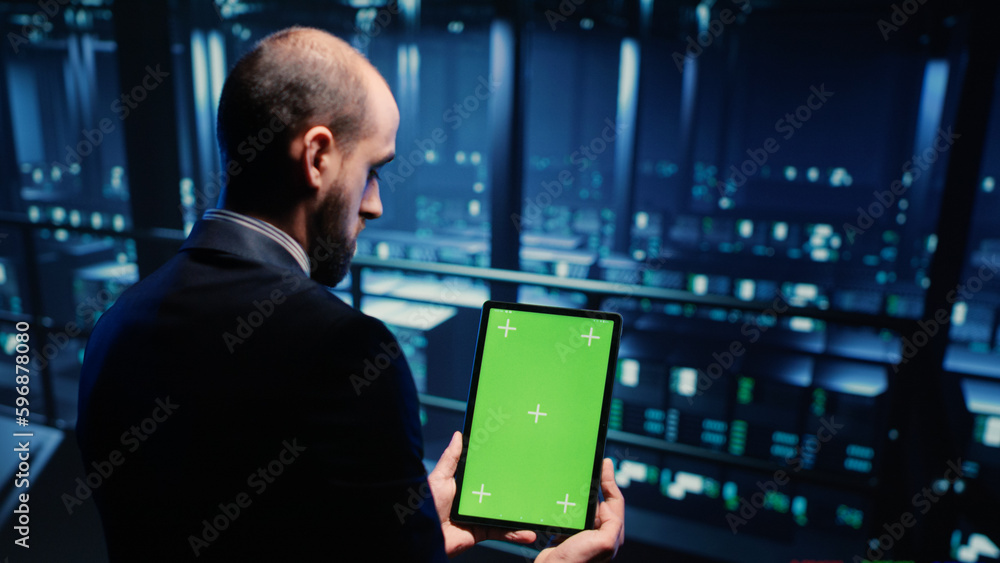 Poster network engineer doing system check on green screen, using tablet showing chroma key display with is