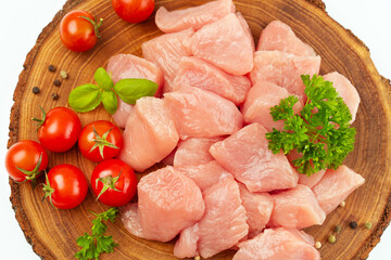 Fresh pieces of turkey meat.Raw chicken.Raw pieces of turkey meat with greens and tomatoes on a wooden board against a white background.Ogranic food and healthy eating.chicken fillet.Close up.