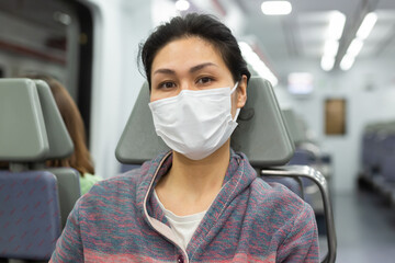 Fototapeta na wymiar Asian woman in protective mask sitting in subway train