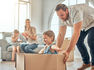 A happy mature caucasian father pushing his daughter in a box while her mother and sister sit on...