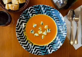 Vegetarian concept. Carrot cream soup served in plate with soft cheese gorgonzola..
