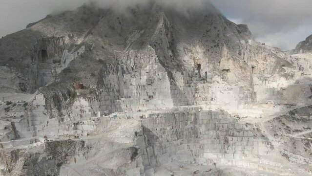 Drone approaches a cloud covered mountain in Carrara, Italy, famous for its huge marble quarry