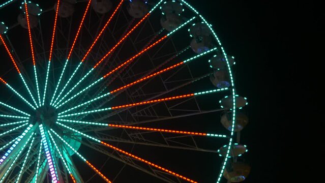 A big festive colorful ferris wheel at night against the background of the night sky. Ferris wheel at night of colorful with outdoor round rotation st Amusement Park, The annual temple event has