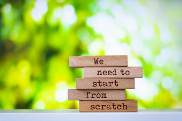 Wooden blocks with words 'We need to start from scratch'. Inspirational motivational quote.