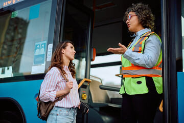 Female driver communicating with commuter at bus station.