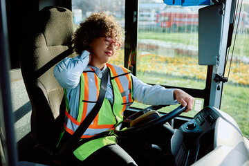 Female bus driver having neck pain while driving.