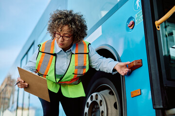 Female driver checking turn signal on bus before ride.