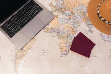 Desk world map with passports, laptop and hat, copy space