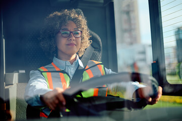 Female school driver behind steering wheel.