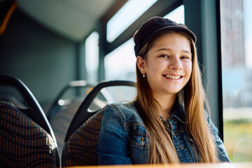 Happy little girl riding in bus and looking at camera.