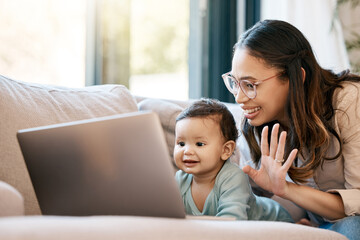 Look who wants to say hi. Shot of a woman waving while sitting with her baby and looking at the laptop.