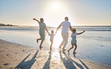 Come this way for a fun time. Rearview shot of a happy family running towards the sea.