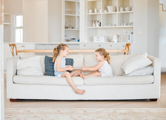 Sharing is caring. Shot of two little sisters fighting over a digital tablet at home.