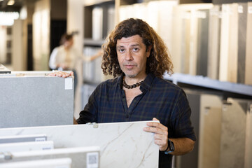 Confident male customer picking out wall tile materials for bathroom in hardware store