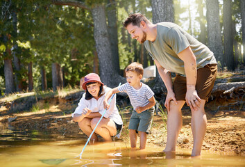 Fototapeta premium Here fishy fishy.... Shot of a happy family playing with a fishing net at a lake in a forest.