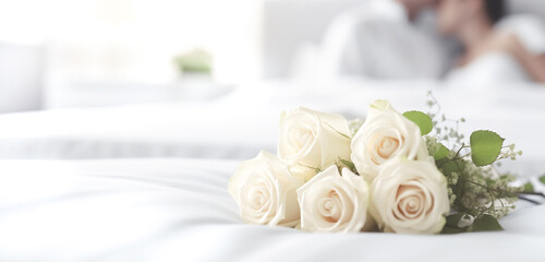 Wedding bouquet of rose flowers on the bed of the newlyweds. Young happy couple in love lying in bed 