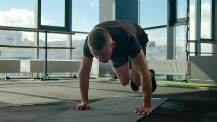 Caucasian sportsman sport trainer doing mountain climber exercise running plank on fitness mat male athlete runner bending knees strong man training endurance healthy lifestyle cardio workout in gym