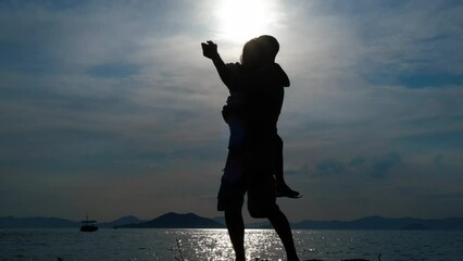 Dance with dad. Silhouette of a father with a daughter in his arms dancing on the seashore. - Powered by Adobe