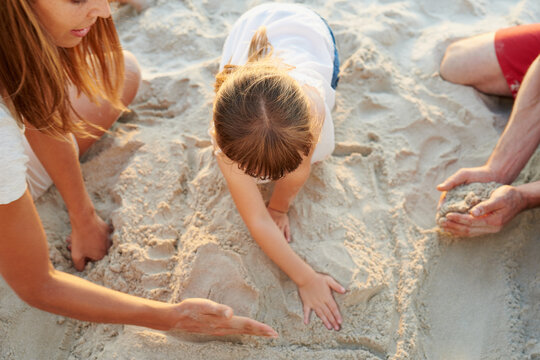 Getting the sand in our toes. Shot of a family drawing shapes in the beach sand together.