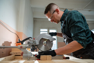 Master cuts the board with a circular saw in the workshop. 