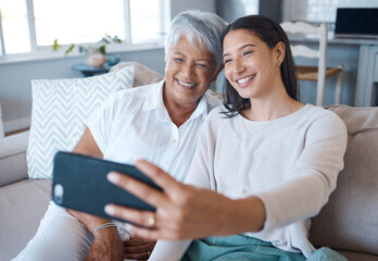 Show them your best smile. Shot of a young woman taking a selfie while bonding with her mother on a...