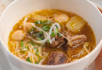 Homemade beef vegetable soup in a white bowl. Delicious noodles soup in a bowl with bread. Meat soup with vegetables