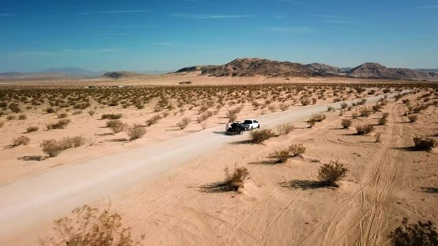 Truck towing trailing on a desert dirt trail