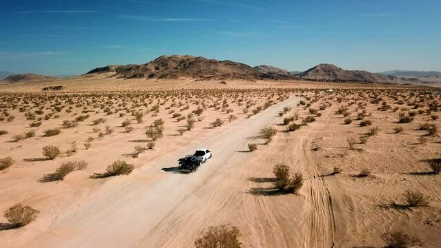 Truck towing trailing on a desert dirt trail
