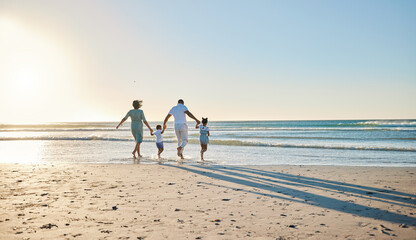 Lets go splish and splash. Rearview shot of a happy family walking towards the sea.