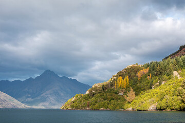 Fototapeta na wymiar Beautiful mountain lake on a cloudy day. Landscape of a large lake in Queenstown, New Zealand. 