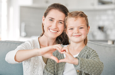 Daughters are born into your heart. Shot of a mother and daughter making a heart sign with their...