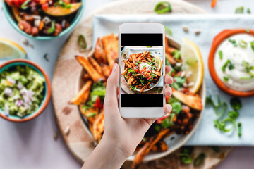 Hand taking a photo of Healthy food with smartphone. Woman using phone mobile apps make digital...