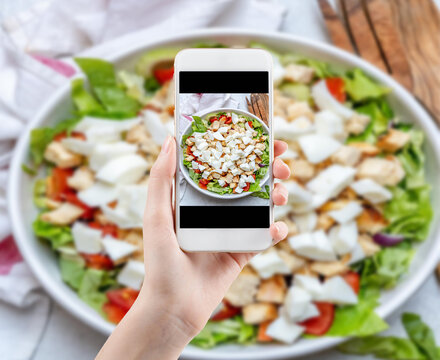 Hand taking a photo of Healthy food with smartphone. Woman using phone mobile apps make digital picture on screen of diet nutrition Vegetarian salad on table, top view