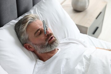 Man sleeping with clothespin on his nose in bed at home. Problem with snoring