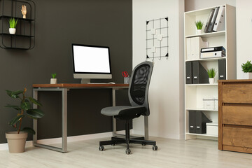Fototapeta premium Stylish office interior with comfortable chair, desk and computer
